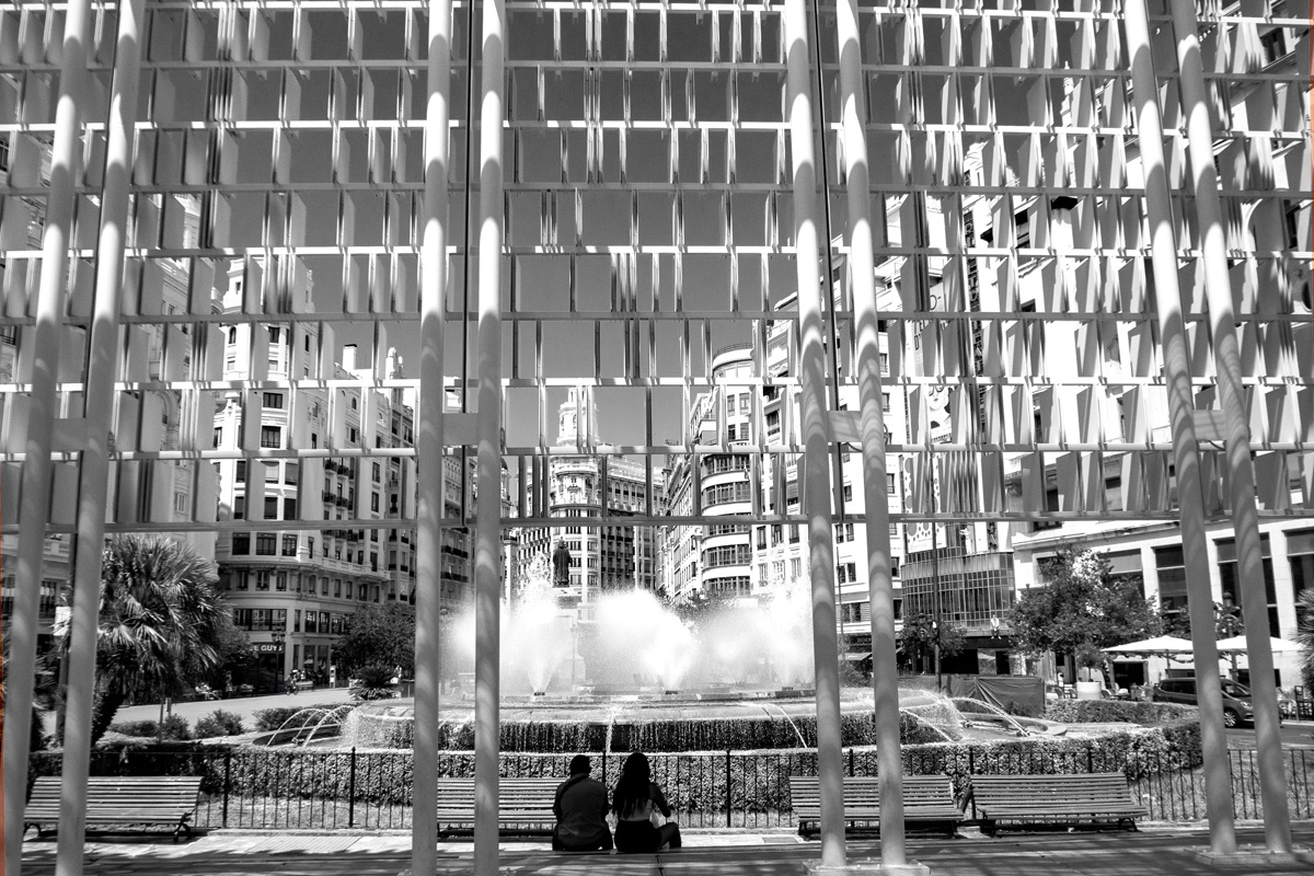 couple-sitting-on-park-bench-on-city-square-valencia